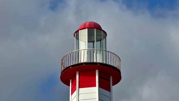 A red and white lighthouse with a blue sky photo