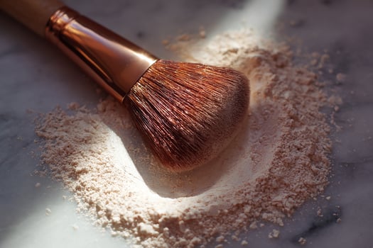 Powder highlighter with brush showing swiped mark on clean surface for makeup and beauty routine photo