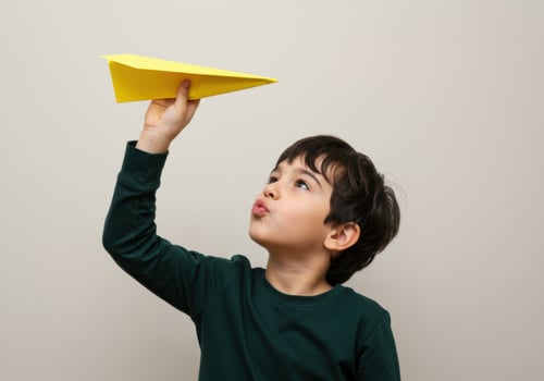 Young boy holding a yellow paper airplane, ready to fly, with a playful expression photo