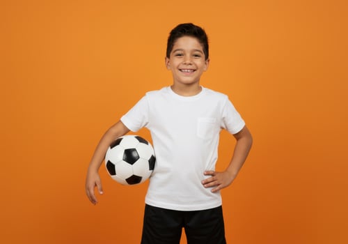 Smiling boy holding a soccer ball ready for a game photo