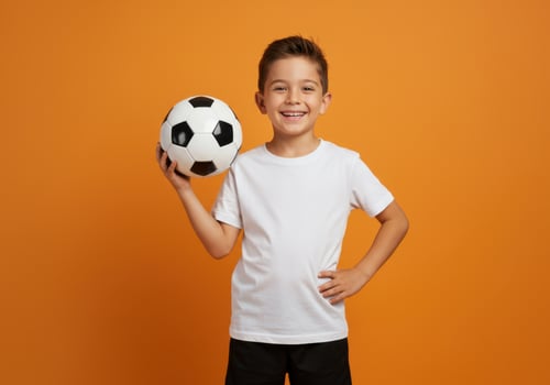 portrait of a happy little boy holding a soccer ball isolated on an orange background photo