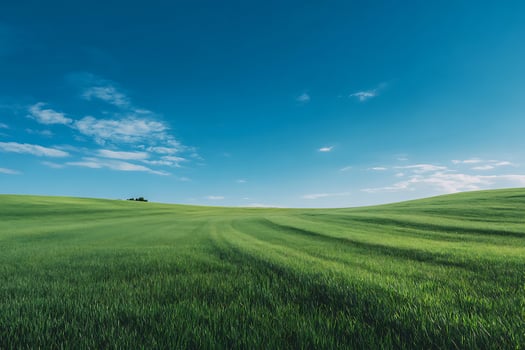 Expansive Green Rolling Hills Landscape with Bright Blue Sky and Wispy Clouds photo
