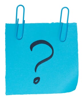 A sheet of blue paper with a black question mark drawn on it, attached with two blue paper clips on an isolated background photo