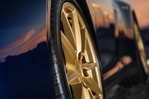 Reflection of Sunset on a Sleek Golden Alloy Car Wheel in an Outdoor Setting photo