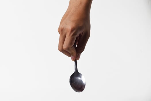 Mans hand holding a downward iron spoon on white background photo