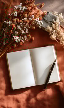 Blank pages of a notebook with a pen and rustic floral arrangement create a cozy autumn ambiance perfect for creative writing planning journal entries or capturing personal photo