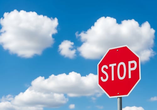 Red octagon stop sign against a bright blue sky with fluffy white clouds photo