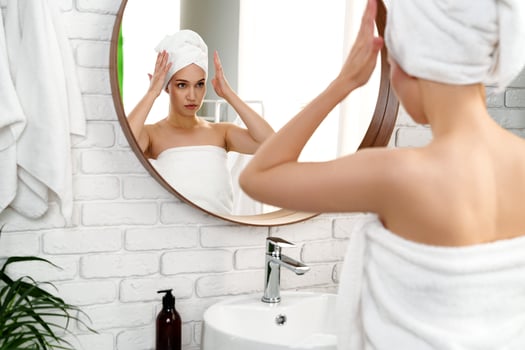 Woman preparing for personal care in a modern bathroom with a mirror and white brick wall photo