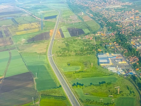 Aerial view of highway and green fields near city. Urban development, agricultural landscape, and transportation network captured from above. photo