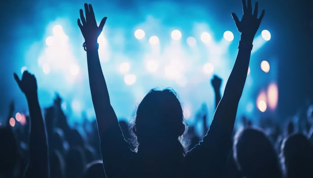 Silhouettes of a crowd at a concert with raised hands, enjoying the show. photo