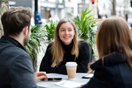 A group of friends sit at a table in a cafe, talking and laughing. photo