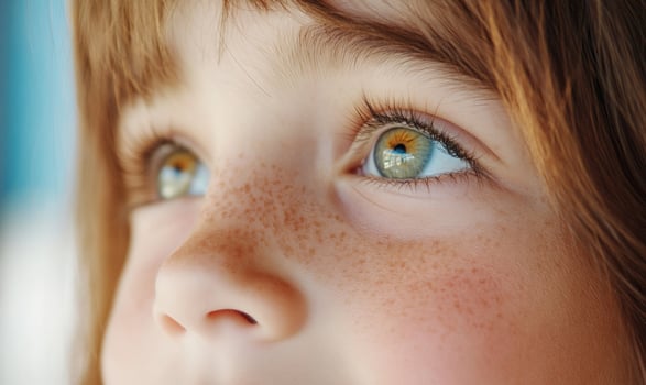Closeup portrait of a young girl with freckles looking up with curious eyes. photo