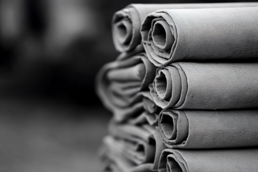 A stack of rolled grey fabric material in a blurred background. photo
