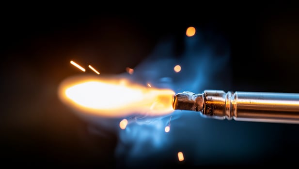 Closeup of a metal rod igniting with sparks and a bright flame on a black background. photo