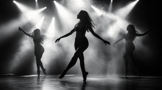 Silhouettes of three female dancers in a spotlight on a stage. photo