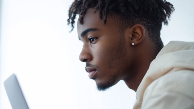 Profile of a young man looking at a tablet with a serious expression. photo