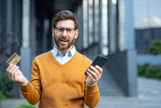 Confused man with phone and credit card photo