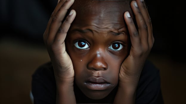 Worried child expressing sadness and concern with hands on face photo
