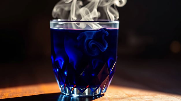 A glass of blue liquid with smoke coming out of it photo