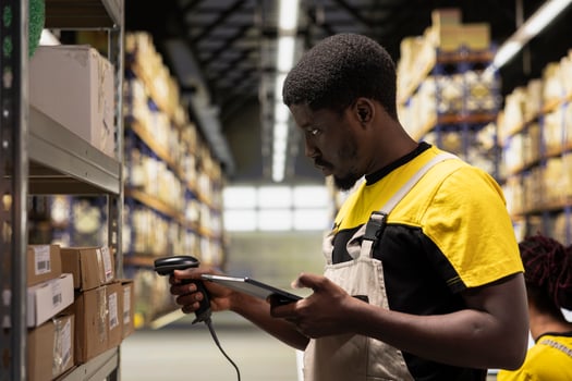 Black staff member using a barcode scanner to process shipping labels on boxes from industrial storage racks. Scanning awb tags for package tracking service with tracking info, accurate logistics. photo
