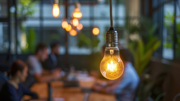 Glowing light bulb illuminates modern office space with collaboration photo