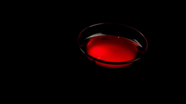A glass of red liquid on a black background photo
