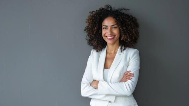Confident woman portrait in white business suit with arms crossed against gray backdrop photo