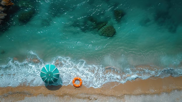 Turquoise ocean waves crashing on sandy beach with umbrella and life preserver aerial view photo