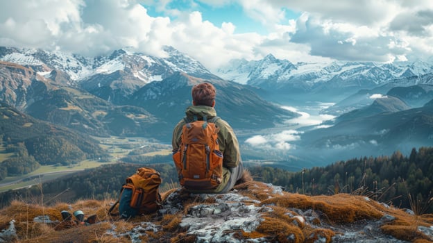 Person backpacking seated admiring mountain range landscape photo