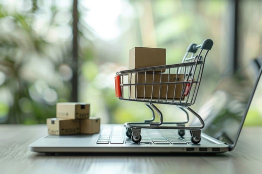 Online shopping with miniature cart and boxes on laptop photo
