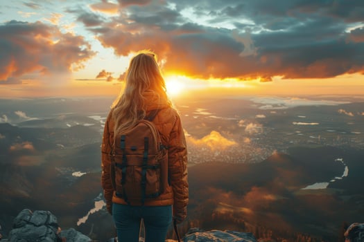 Woman hiker observing mountain sunset with backpack adventure and travel photo
