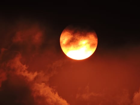 the sun with red sky and black clouds, very horror and scary photo