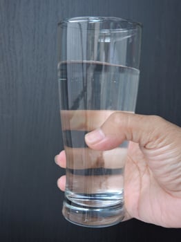 A beer glass filled with refreshing drinking water is held in a hand photo