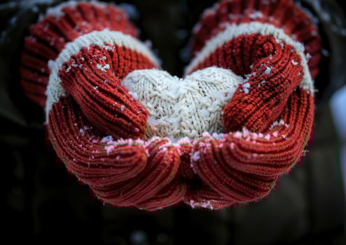 Winter warmth knitted mittens holding a heart in the snow cozy holiday concept photo