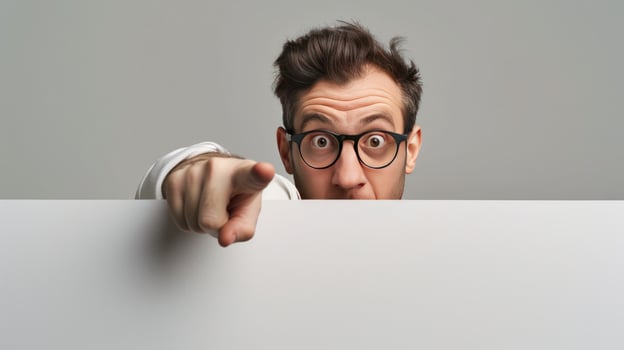 Man pointing finger and peeking over blank board for attention photo
