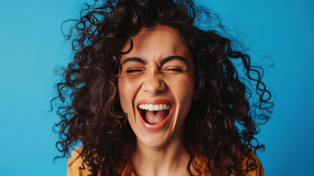 Woman laughing expressing joy and happiness with closed eyes on blue background photo