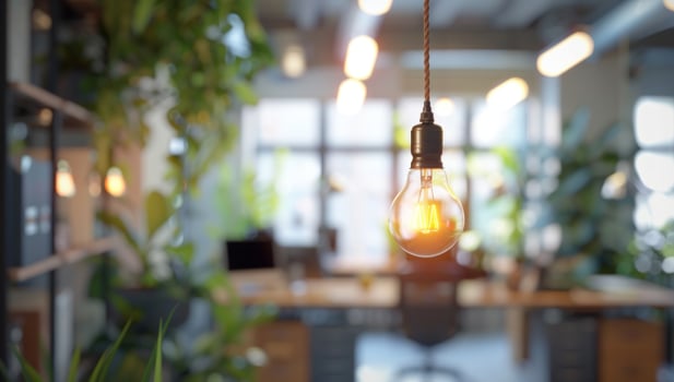 Hanging lightbulb in modern office interior with natural light and green plants photo