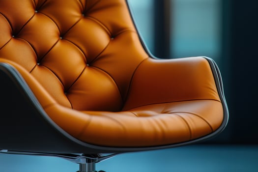 An orange leather chair with a black base photo