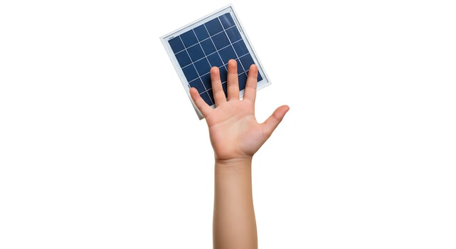 Child's hand holds a small solar panel, representing green energy future photo