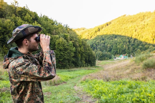 Hunter watching with binoculars in the woods photo