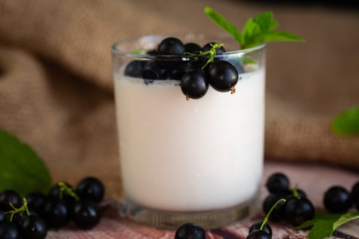 Blackcurrant and homemade yogurt in a transparent glass on a wooden. photo