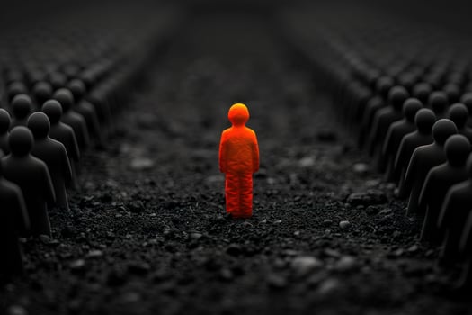 A single, glowing orange figure stands out from a crowd of black figures in a dark, gritty environment. photo