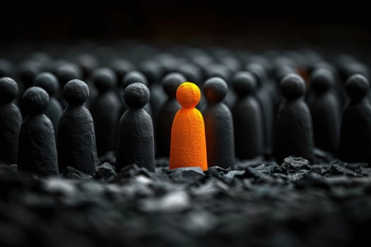 A single orange figure stands out from a crowd of black figures, representing individuality and standing out. photo