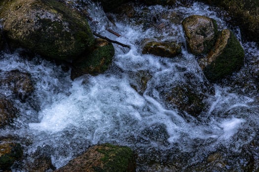Flowing water cascades over rocks in a natural stream setting photo