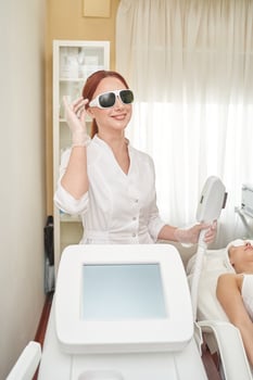 Female caucasian adult beautician preparing laser equipment for skin treatment in clinic. photo