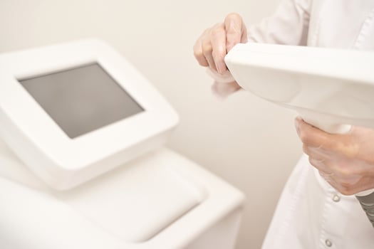 Female technician operating laser hair removal machine in modern clinic setting. photo
