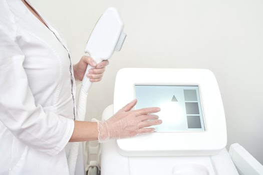 Female technician operating medical laser equipment with touchscreen in modern clinic setting. photo