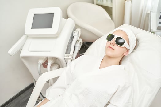 Young caucasian female relaxing during laser facial treatment in a modern beauty clinic. photo