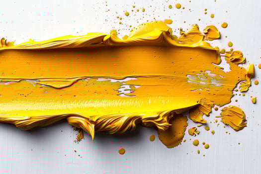 A yellow paint stroke with splatters on a white background. photo