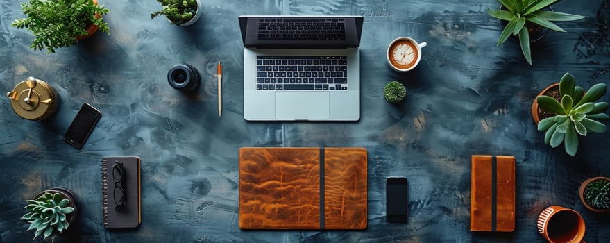 Flat lay of a laptop, phone, coffee cup and other office supplies on a textured desk with plants. photo